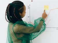 Focused woman points to financial graph, showcasing analysis & strategy.